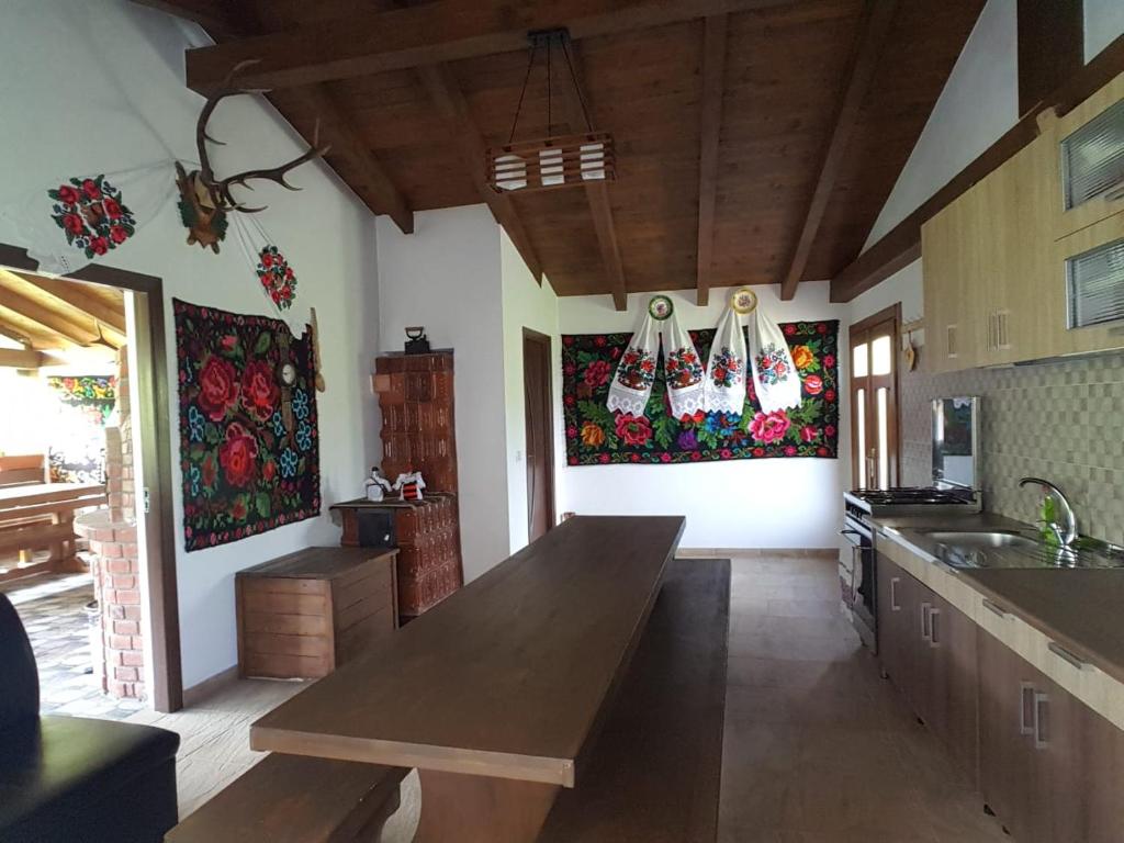 Interior cu masă lungă din lemn, bucătărie și țesături tradiționale din Maramureș pe pereți