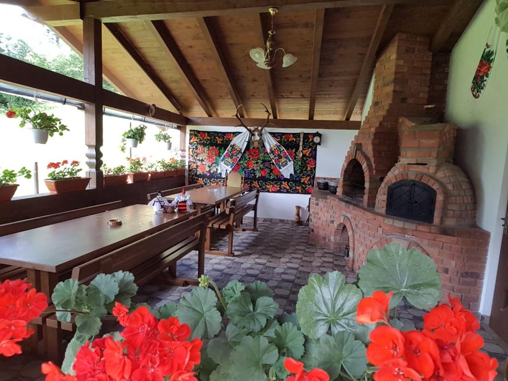 Terasa acoperită cu cuptor de pâine din cărămidă, bănci de lemn și mușcate roșii la ferestre